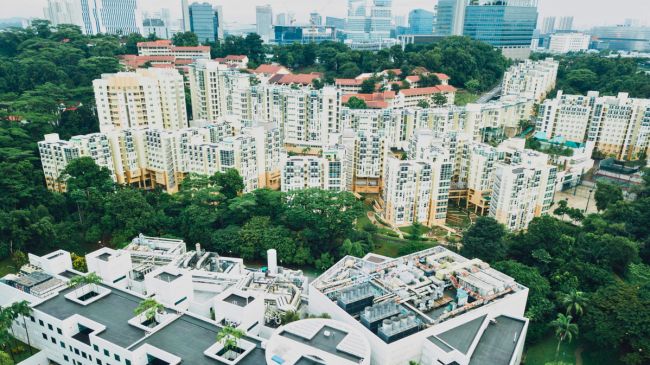 Sustainable Green Infrastructure in an urban setting, with rooftop gardens on a building amidst a backdrop of high-rise apartments and verdant trees.