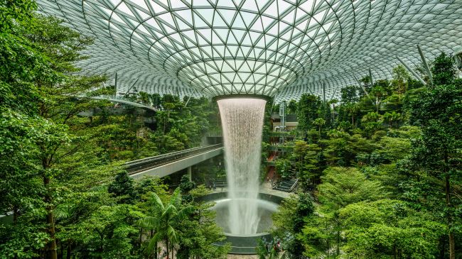 Indoor waterfall within Singapore's Sponge City initiative, showcasing SuDS in a verdant atrium beneath a geometric glass dome.