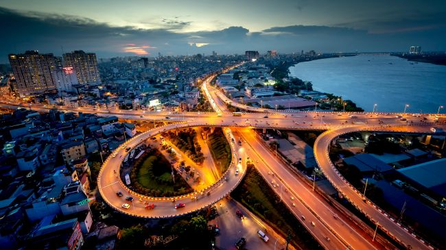 A bustling cityscape at dusk with a multi-level interchange showcasing effective road design for improved traffic flow.